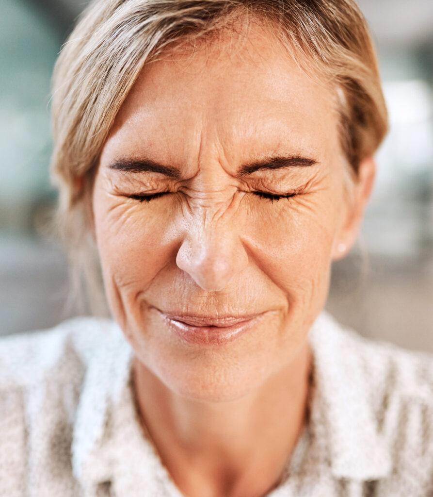 Frau mit schmerzverzerrtem Gesicht am Schreibtisch