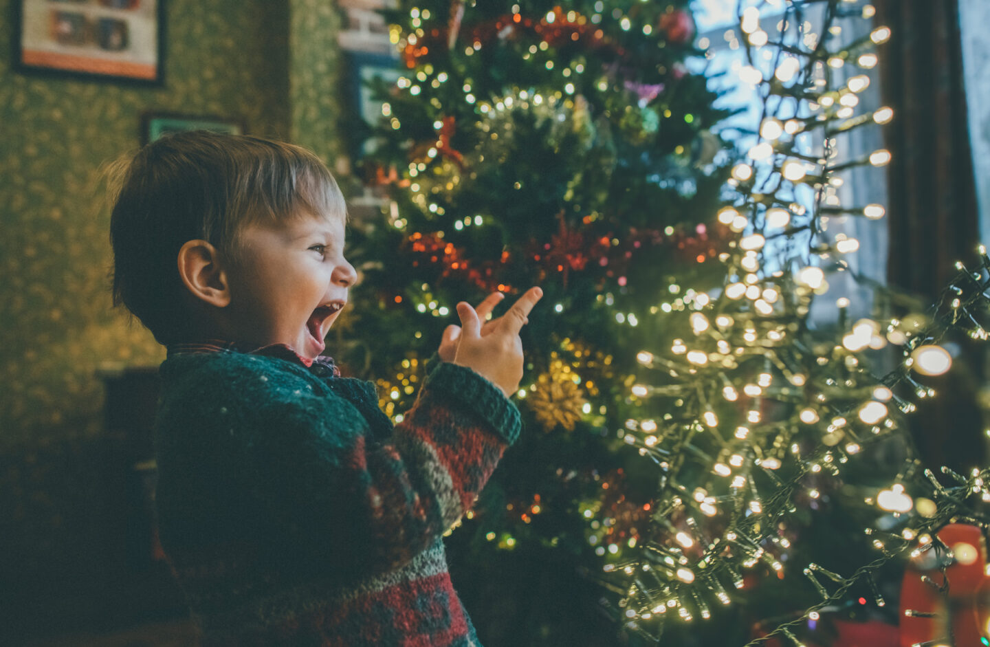 Kleinkind lacht unter dem Weihnachtsbaum