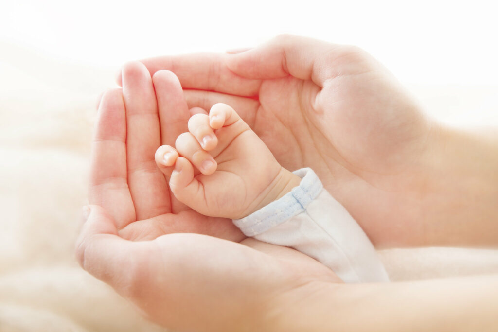 Mutterhände schützen Babyhand