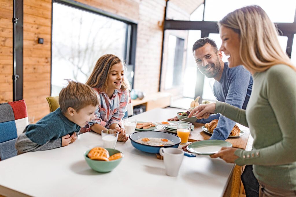 Familie sitzt am Frühstückstisch bei Spiegelei