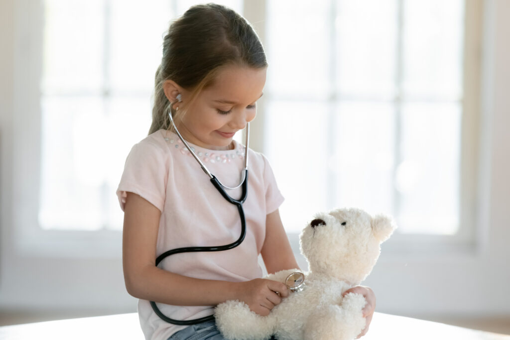 Mädchen spielt mit Teddy Ärztin und hört ihn ab