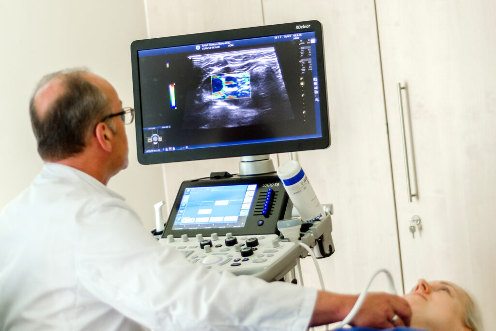 Hals-Nasen-Ohren-Arzt untersucht Patientin mittels Ultraschall an der Schilddrüse
