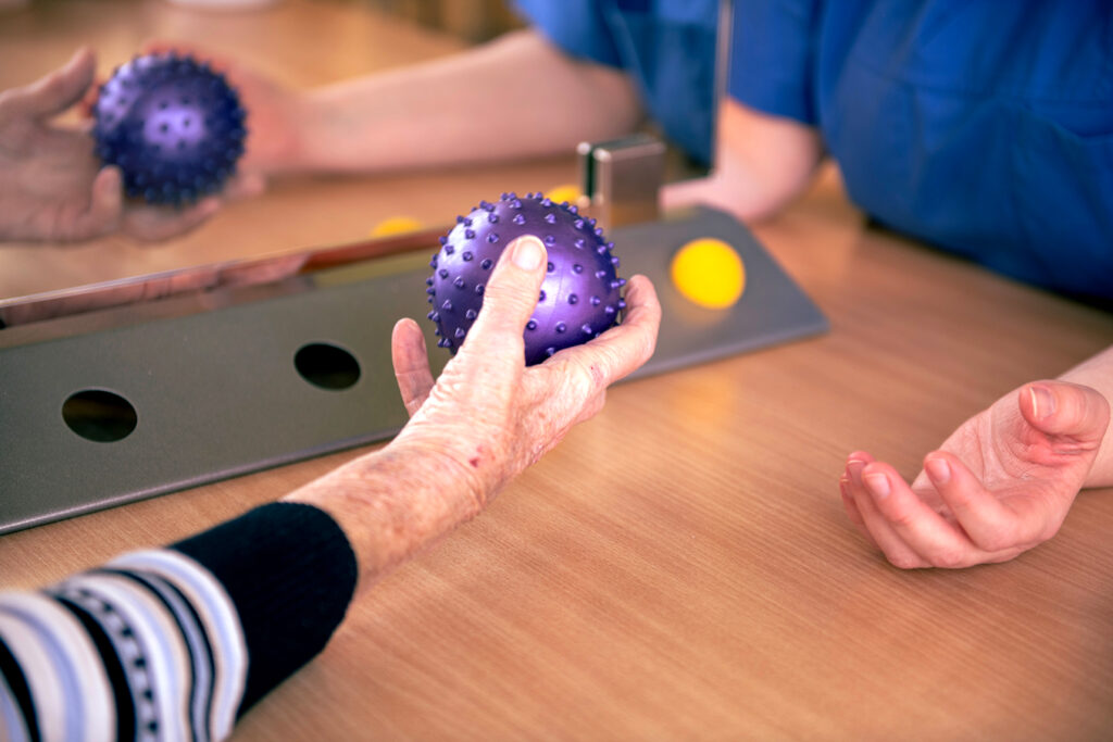 Patientin bei Handtherapie mittels Stachelball in der Ergotherapie