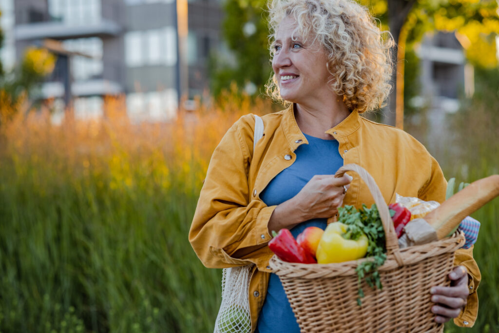 Lebensfrohe und gesunde Frau im mittleren Alter beim Einkaufen von Obst und Gemüse.