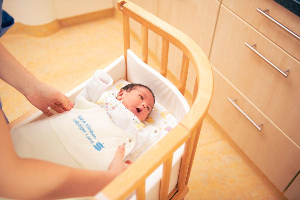 Ein neugeborenes Baby im Kinderbett wird von einer Kinderkrankenschwester umsorgt