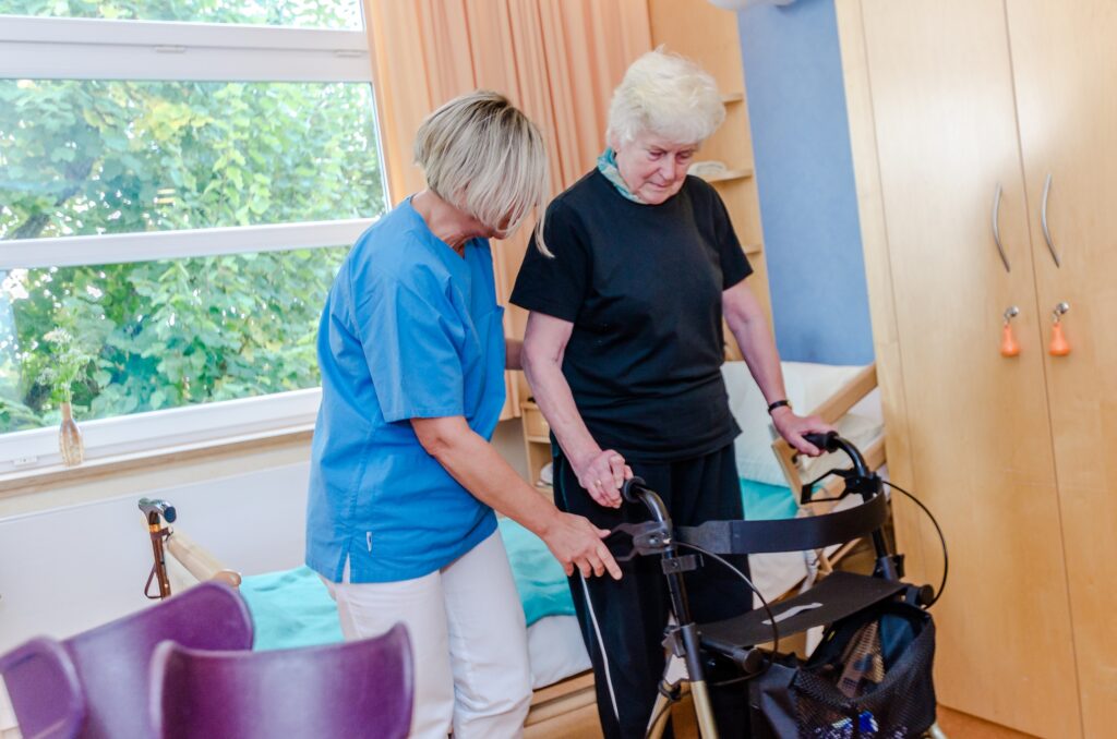 Patientin erhält Unterstützung mit dem Rollator