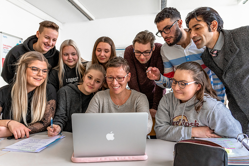 Schüler:innen des Bildungszentrums Leipziger lLnd sitzen um ein Notebook versammelt und schauen auf den Bildschirm