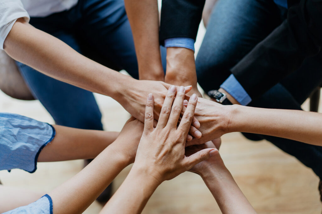 Image of a group of business people stacking hands in office