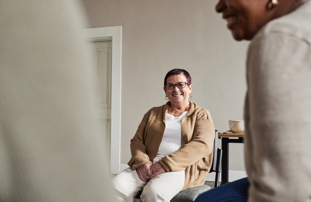 Group therapy and senior woman with smile at meeting for discussion on help and support.